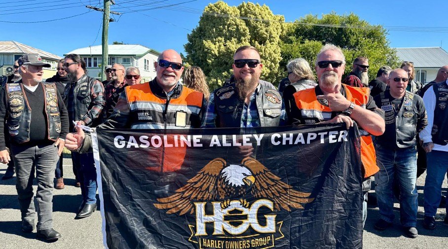 Ride Captain Shaneo standing with Tail End Charlies Pricey and Greg behind the Gasoline Alley Chapter banner