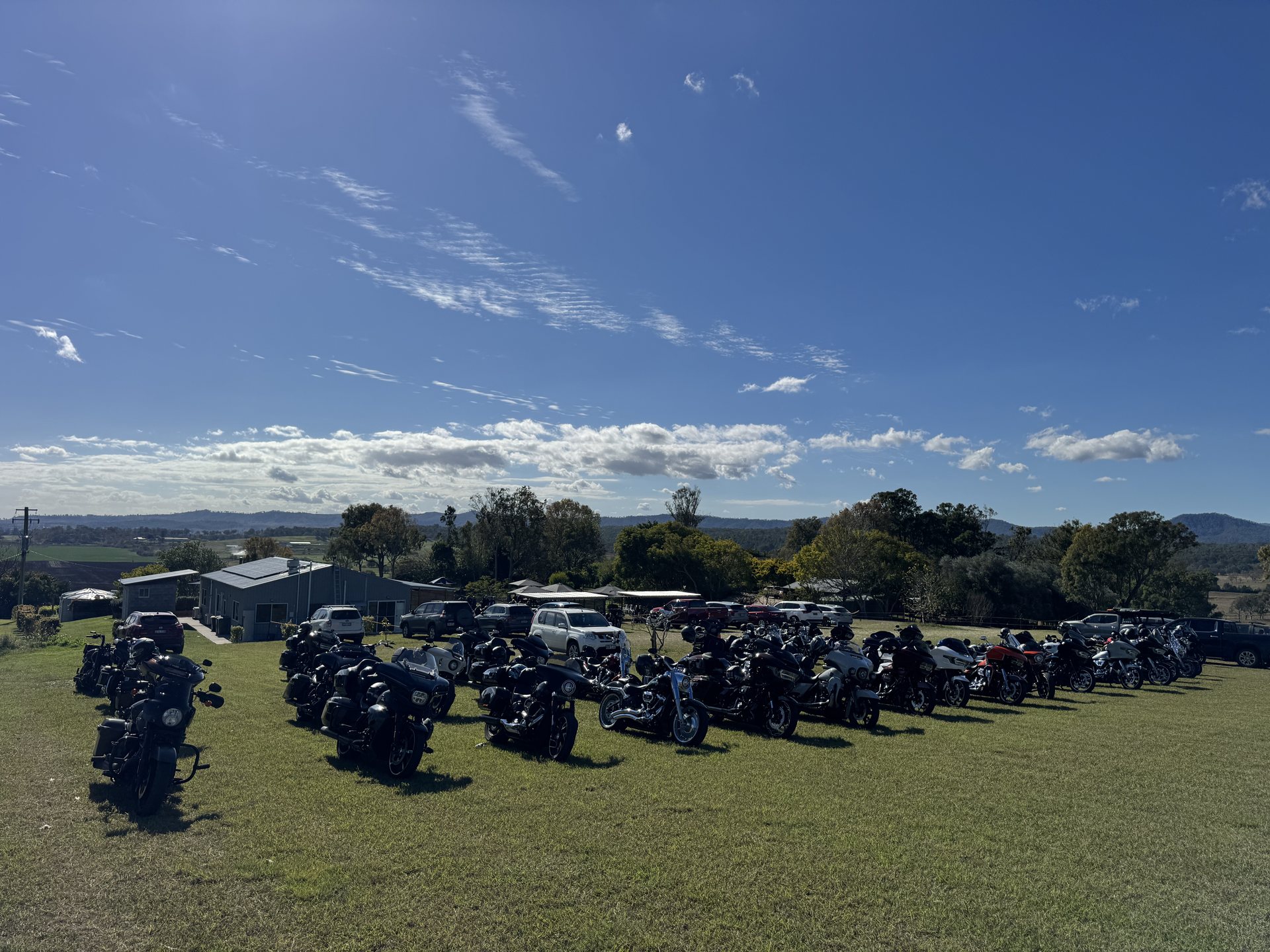 Chapter motorcycles parked on the grass under blue skies at Oaky Creek Farm