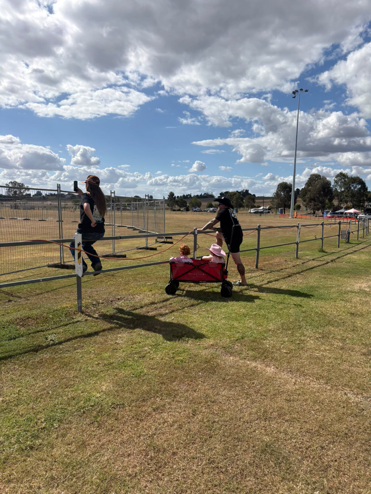 Children riding in a red wagon at Kalbar Showgrounds, photographed from behind