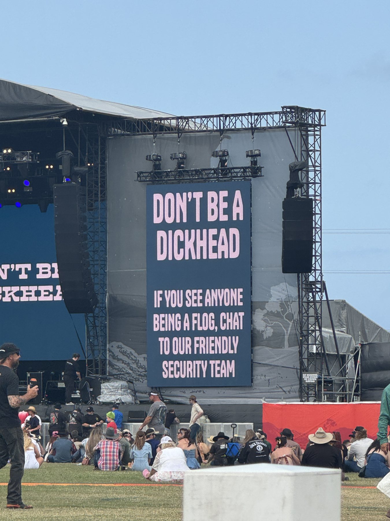 A humorous festival security sign beside the main stage