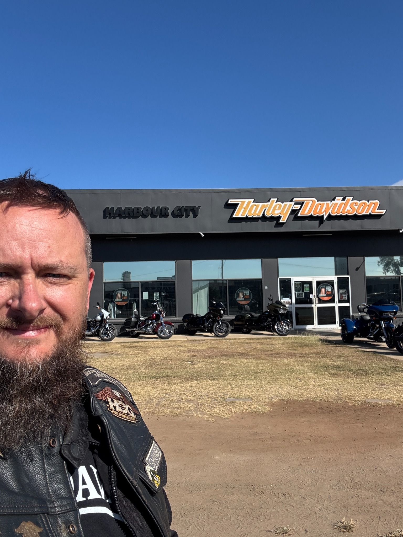 Selfie outside Harbour City Harley-Davidson with motorcycles parked in front.