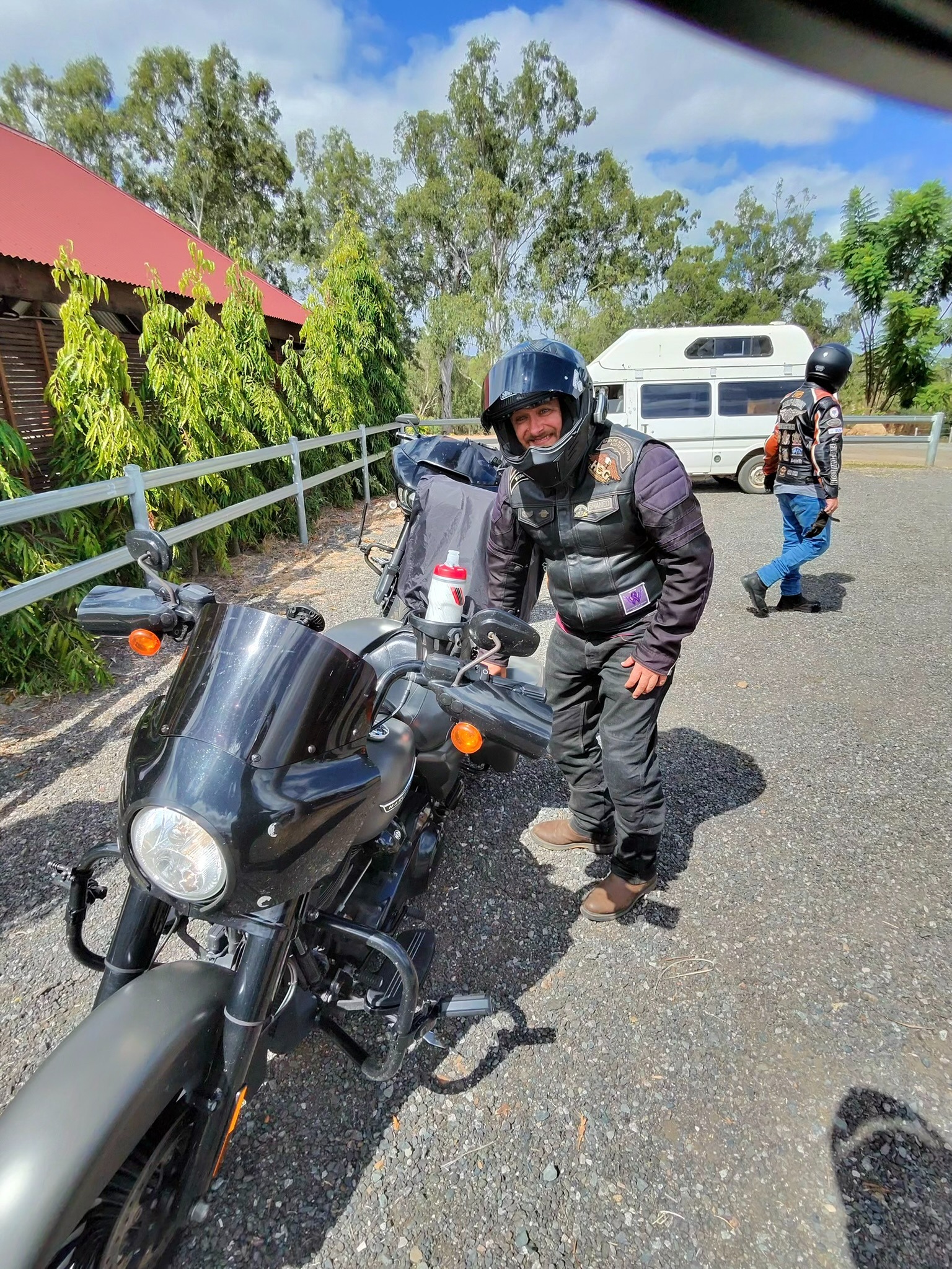 A rider standing beside a Harley-Davidson during a roadside stop.