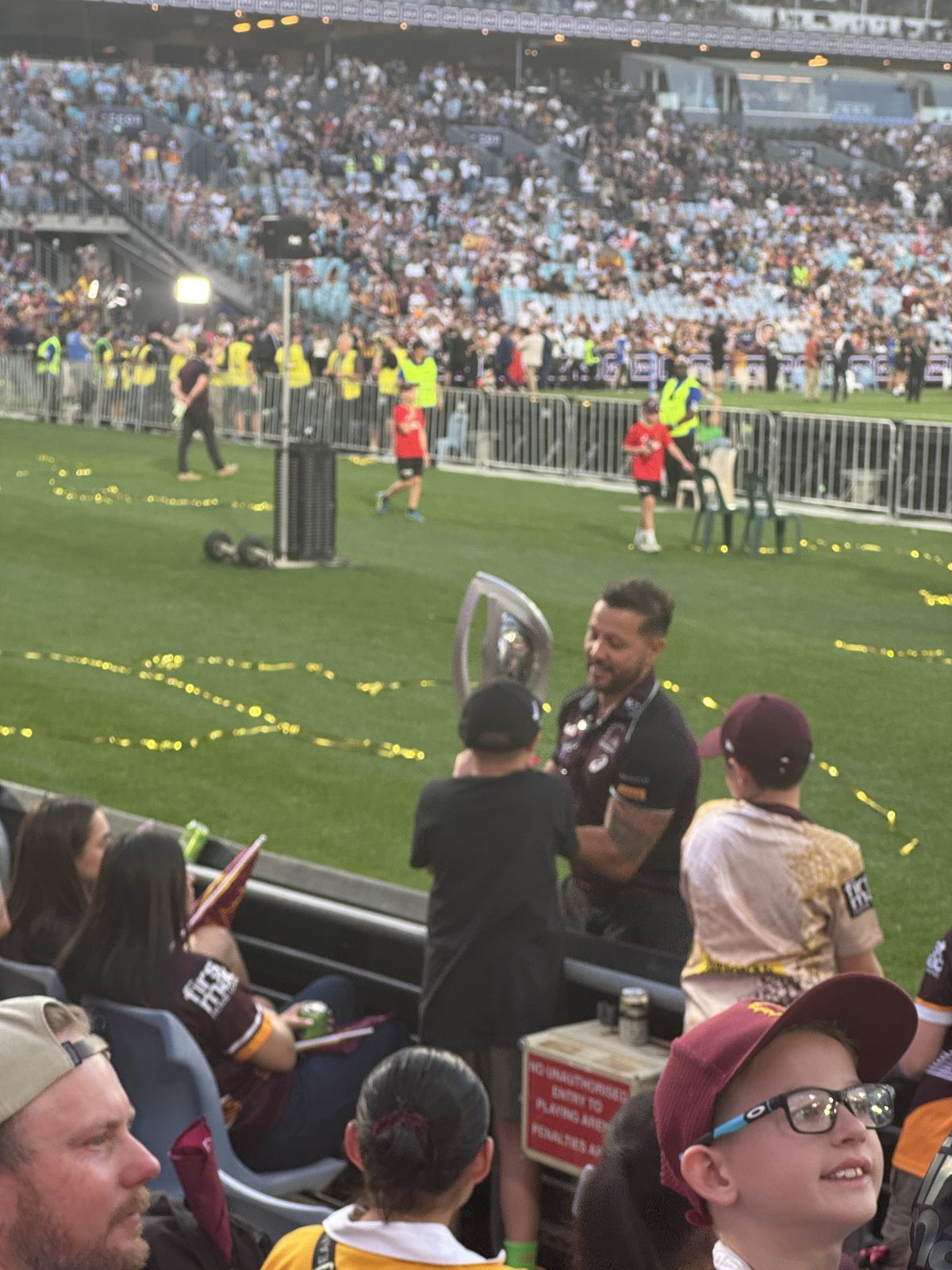 The NRL premiership trophy being carried past supporters after the Grand Final