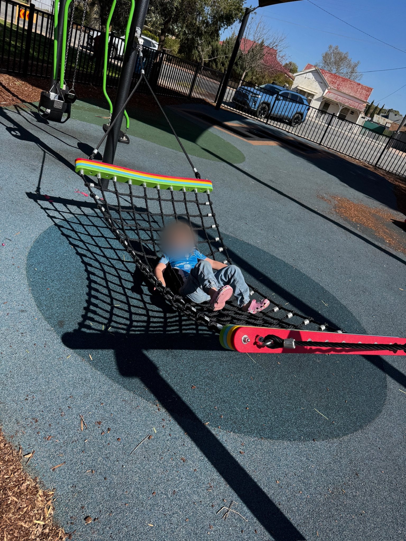 A child lying back in a playground basket swing.