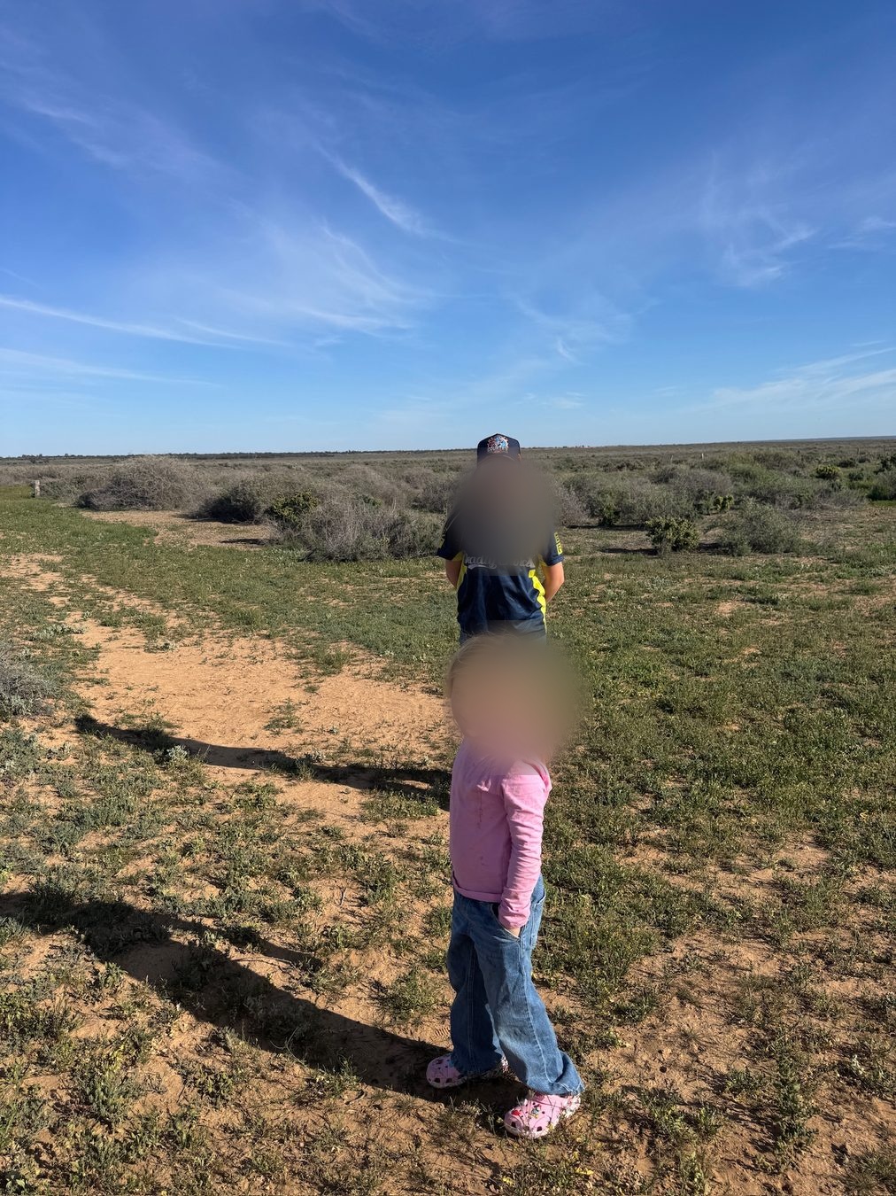 Family members walking along a sandy track through the scrub.