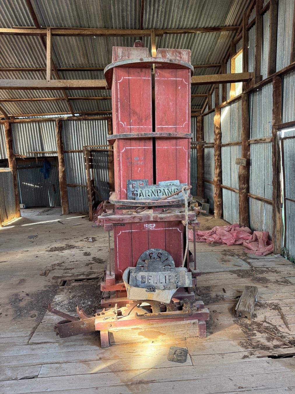 A tall piece of rusted agricultural machinery inside a shed.