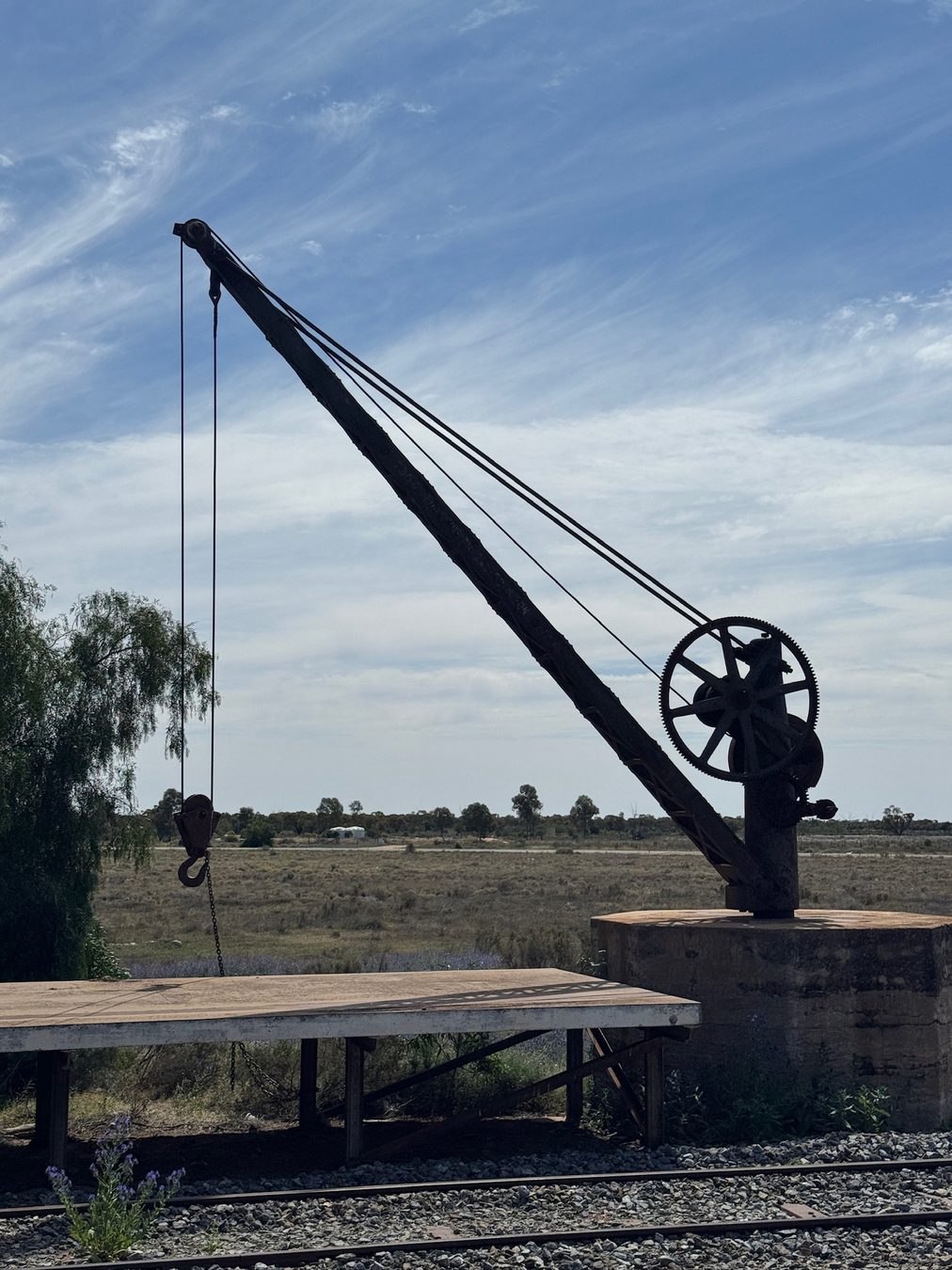 A historic railway crane silhouetted against the sky.