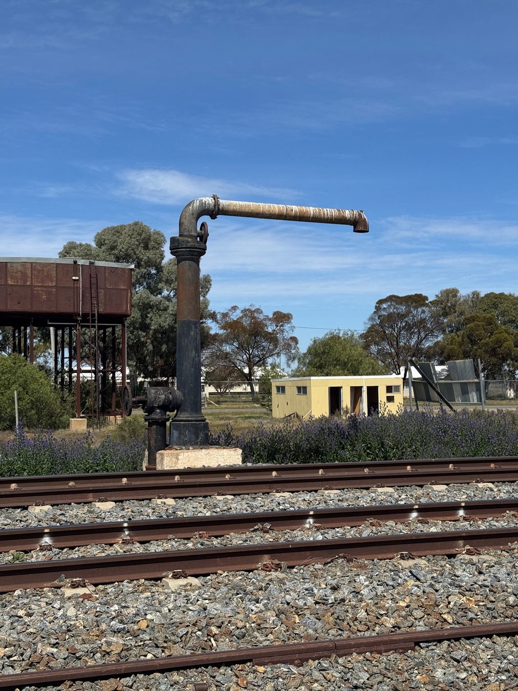An old railway water crane beside the tracks.