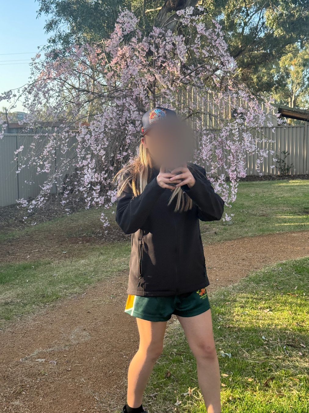 A smiling teenager beneath flowering branches in the garden.