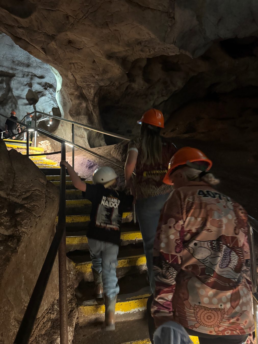 Family members in safety helmets on the cave stairs.